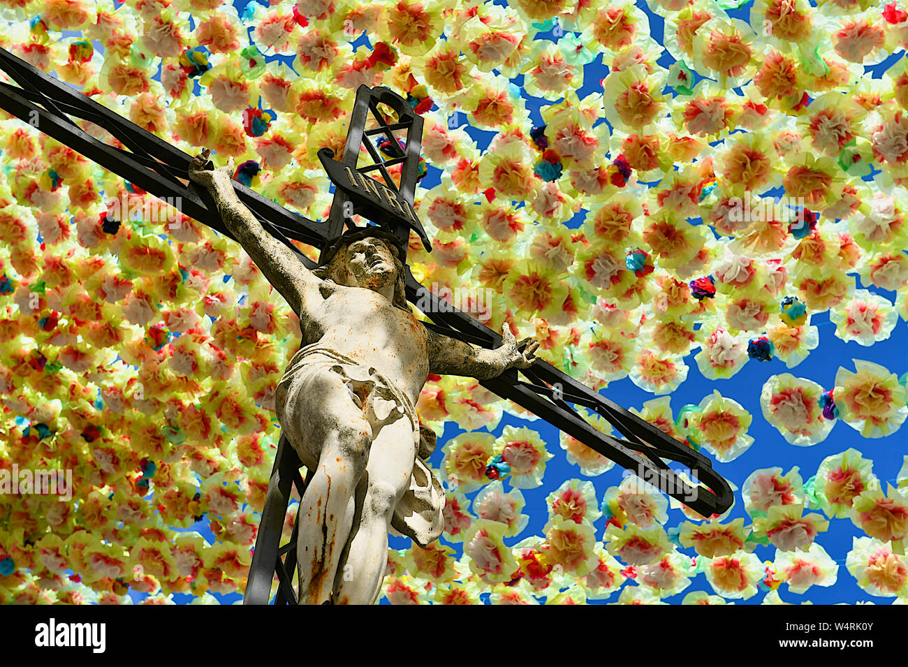 Jesus Christ on cross below hanging flowers, France Stock Photo