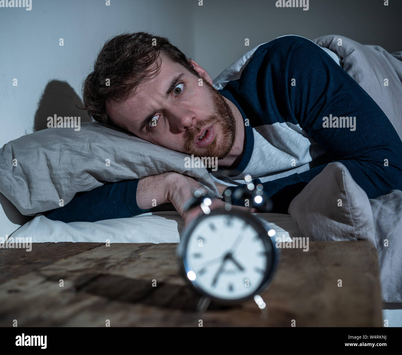 Insomnia Stress and Sleeping disorder concept. Sleepless desperate young caucasian man awake at night not able to sleep, feeling frustrated and worrie Stock Photo