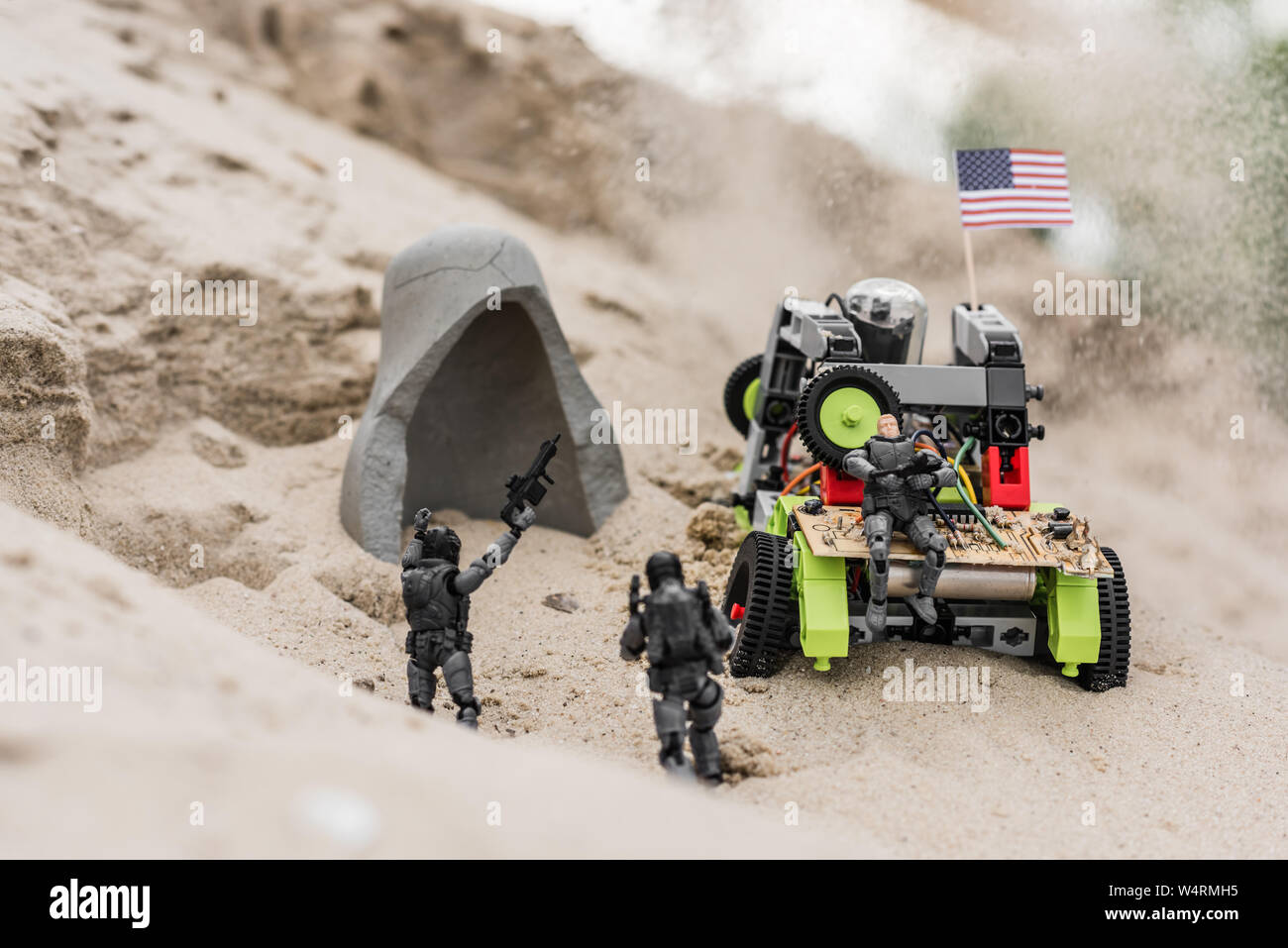 plastic toy soldiers on sand dune near car with american flag and cave Stock Photo
