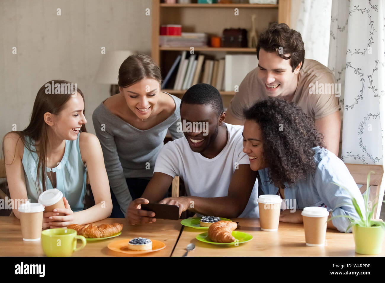 Happy black guy showing funny videos on smartphone. Stock Photo