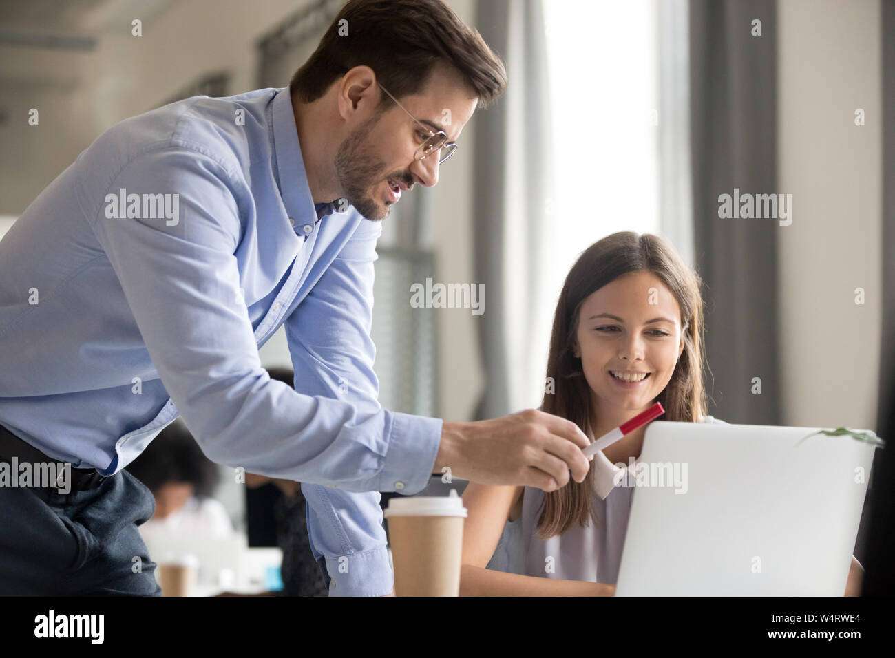 Mentor explaining task to smiling female employee Stock Photo