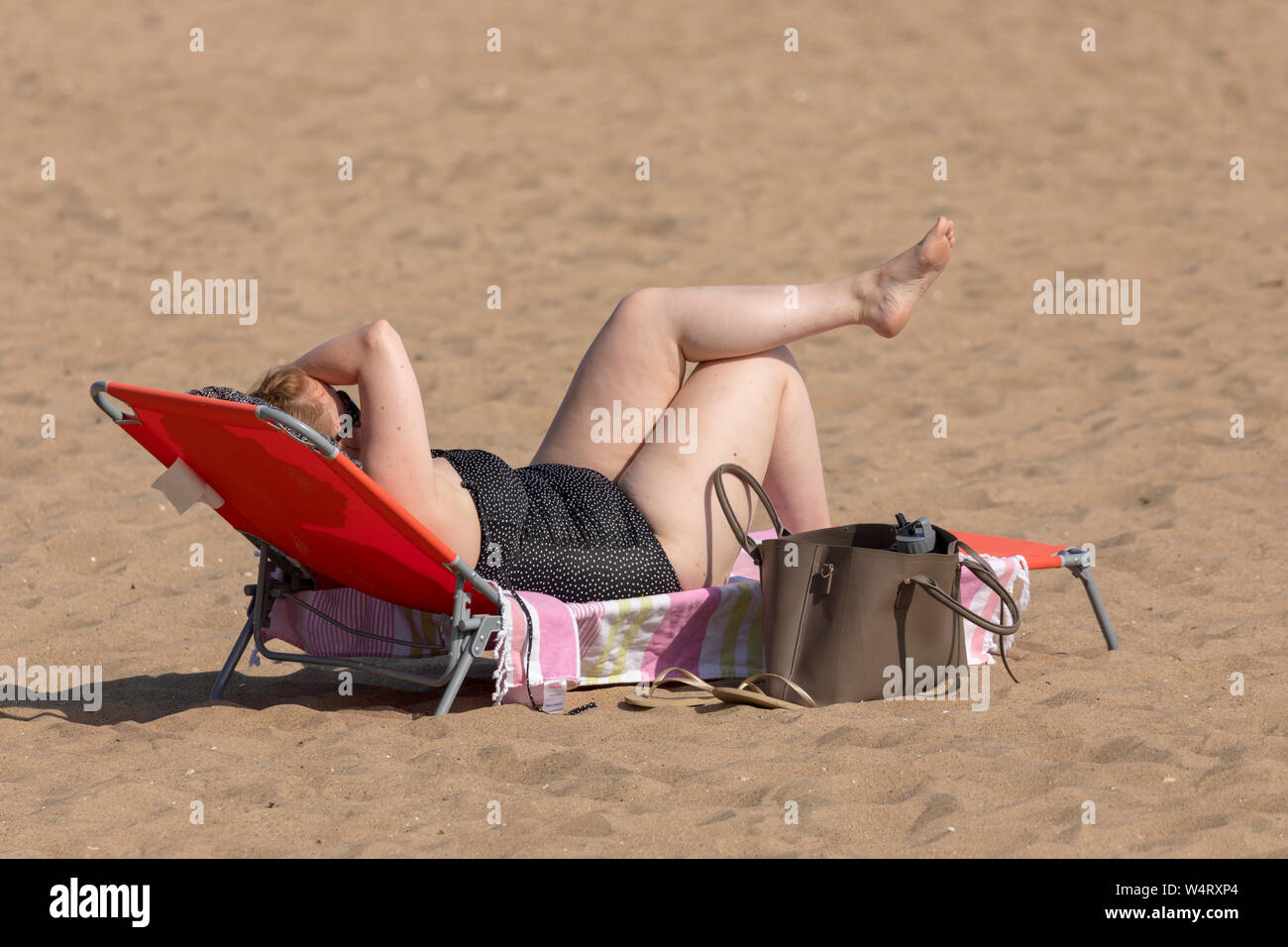 North Wales, UK. 25th July, 2019. UK Weather: Heatwave weather could break UK all time records today for some parts of the UK with temperatures expected to reach the 39C for the south east with many parts above 30C. The North Wales coastline bathed in hot sunshine as the heatwave reaches its peak today as a beach visitor relaxes on Cowlyn Bay Beach, North Wales. Credit: DGDImages/Alamy Live News Stock Photo