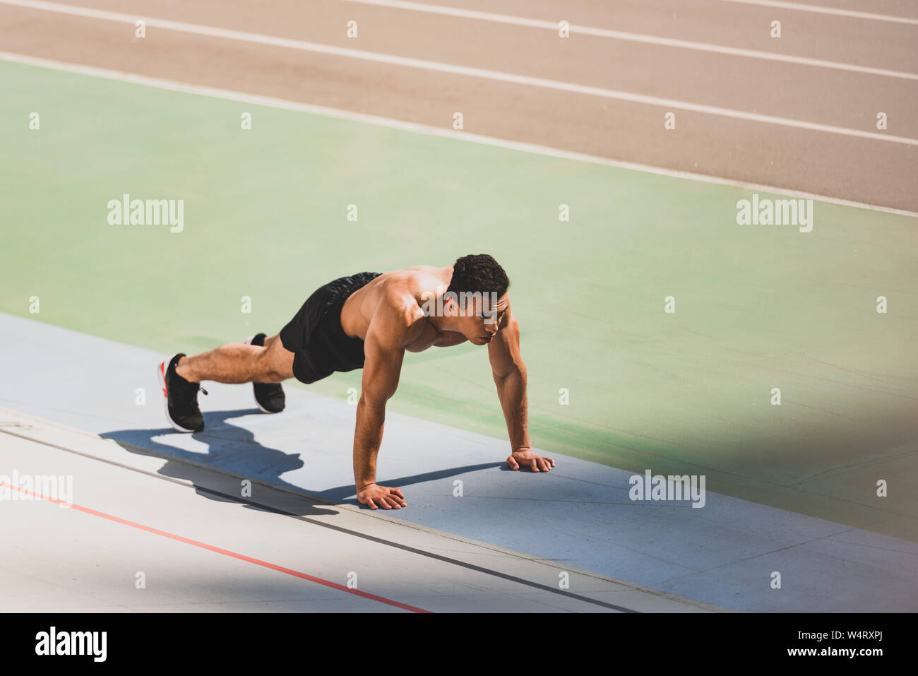 mixed race sportsman standing in plank at stadium Stock Photo - Alamy