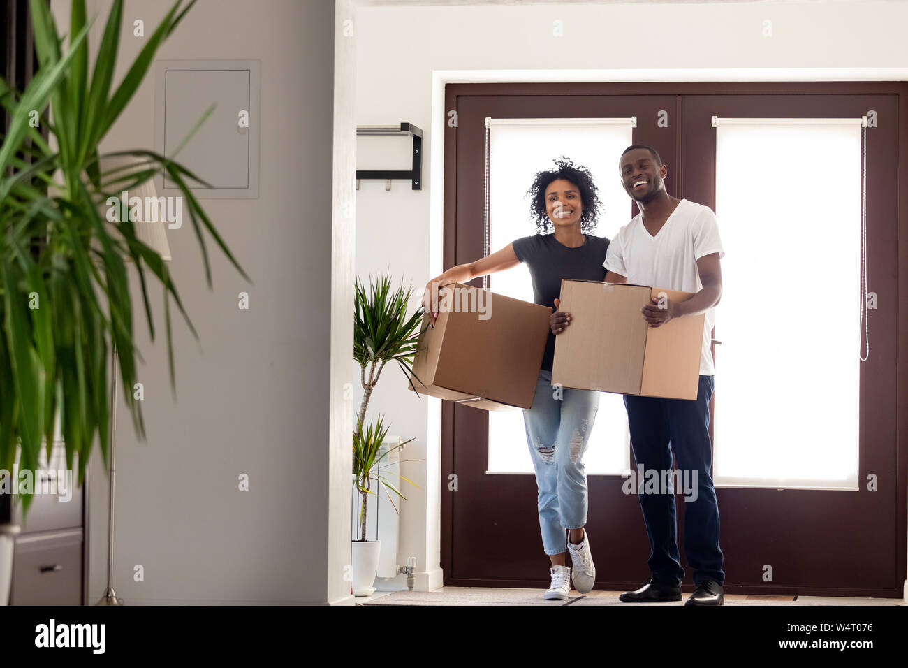Happy african couple holding big boxes entering modern house Stock ...