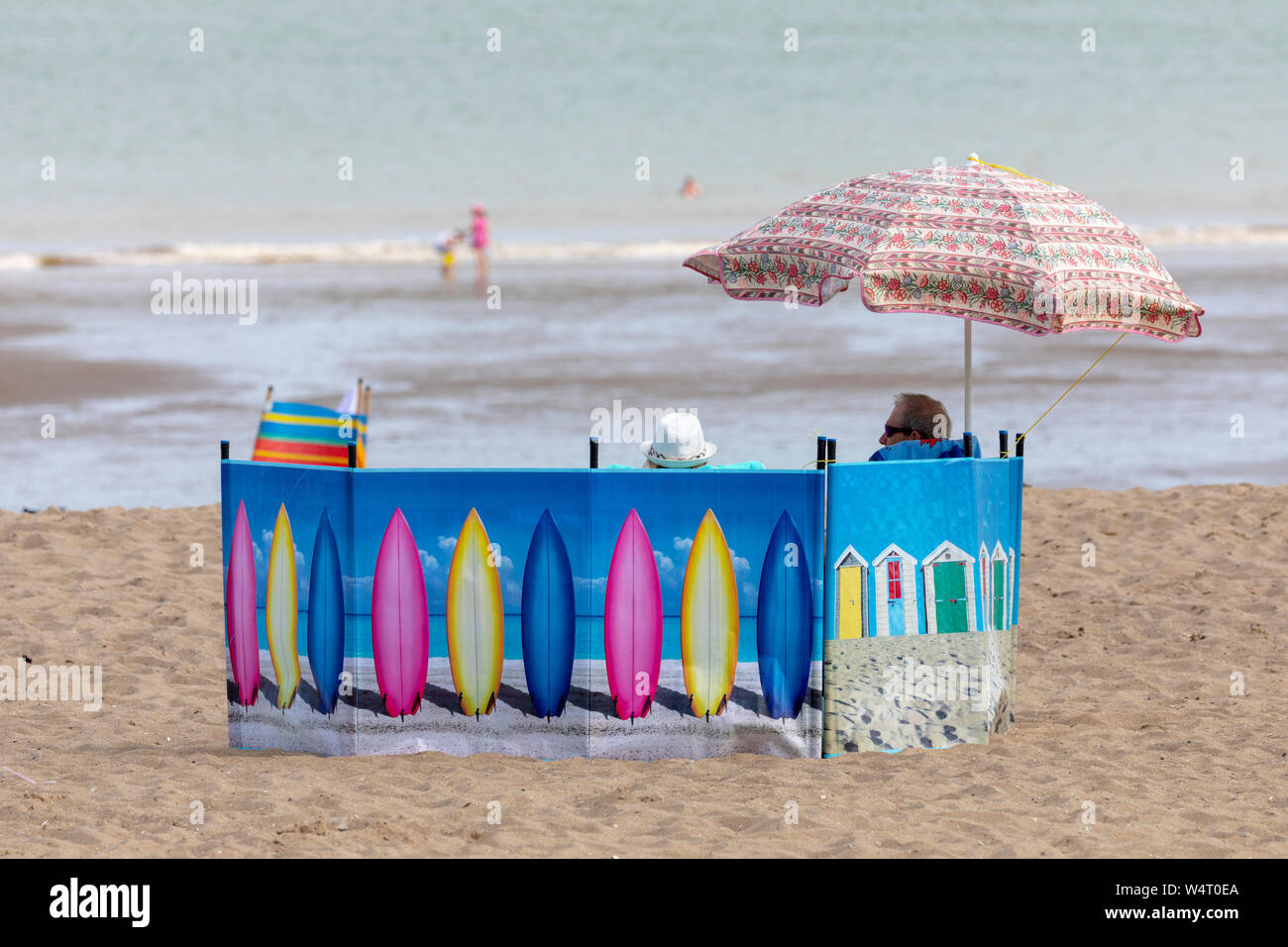 North Wales, UK 25th July 2019. UK Weather:  Heatwave weather could break UK all time records today for some parts of the UK with temperatures expected to reach the 39C for the south east with many parts above 30C. The North Wales coastline bathed in hot sunshine as the heatwave reaches its peak today as this couple discovered beneath their shade on the beach at Colwyn Bay, North Wales © DGDImages/AlamyLiveNews Stock Photo