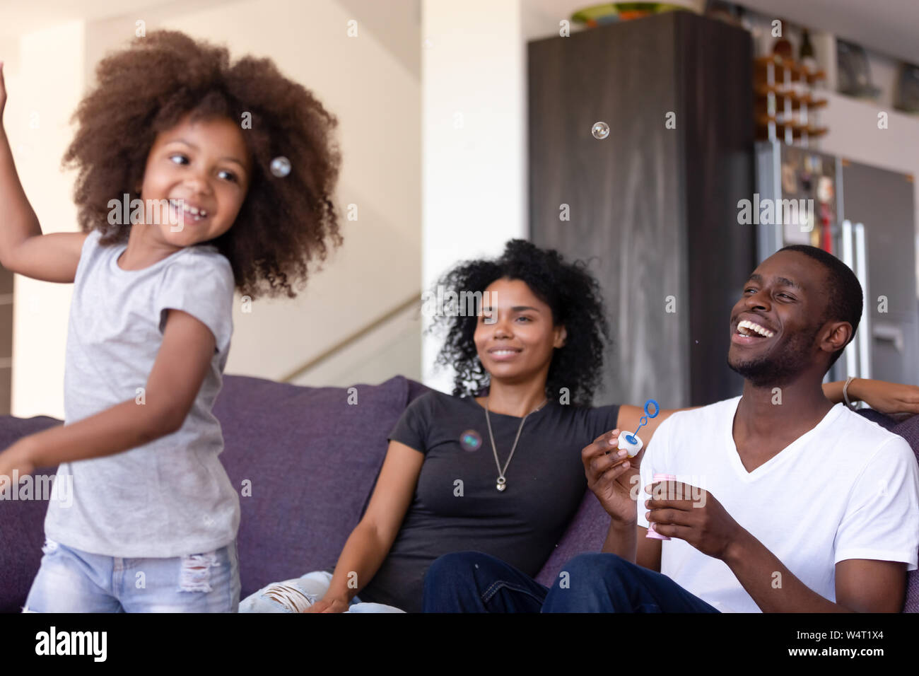 Family having fun with kid and soap bubbles at home Stock Photo