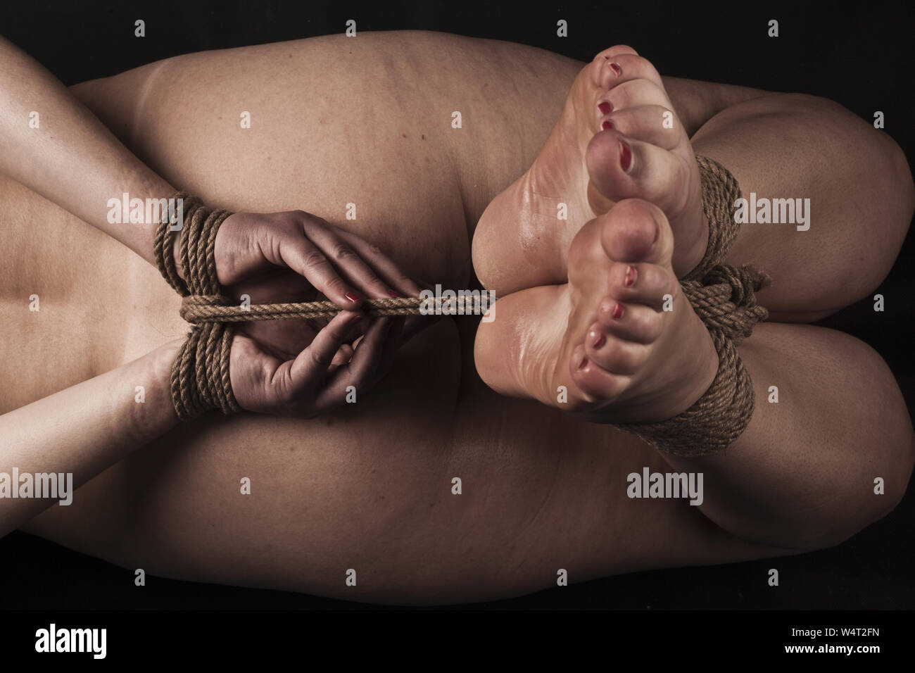 Submissive woman in hog tie bondage position on black background  BDSM  theme Stock Photo - Alamy