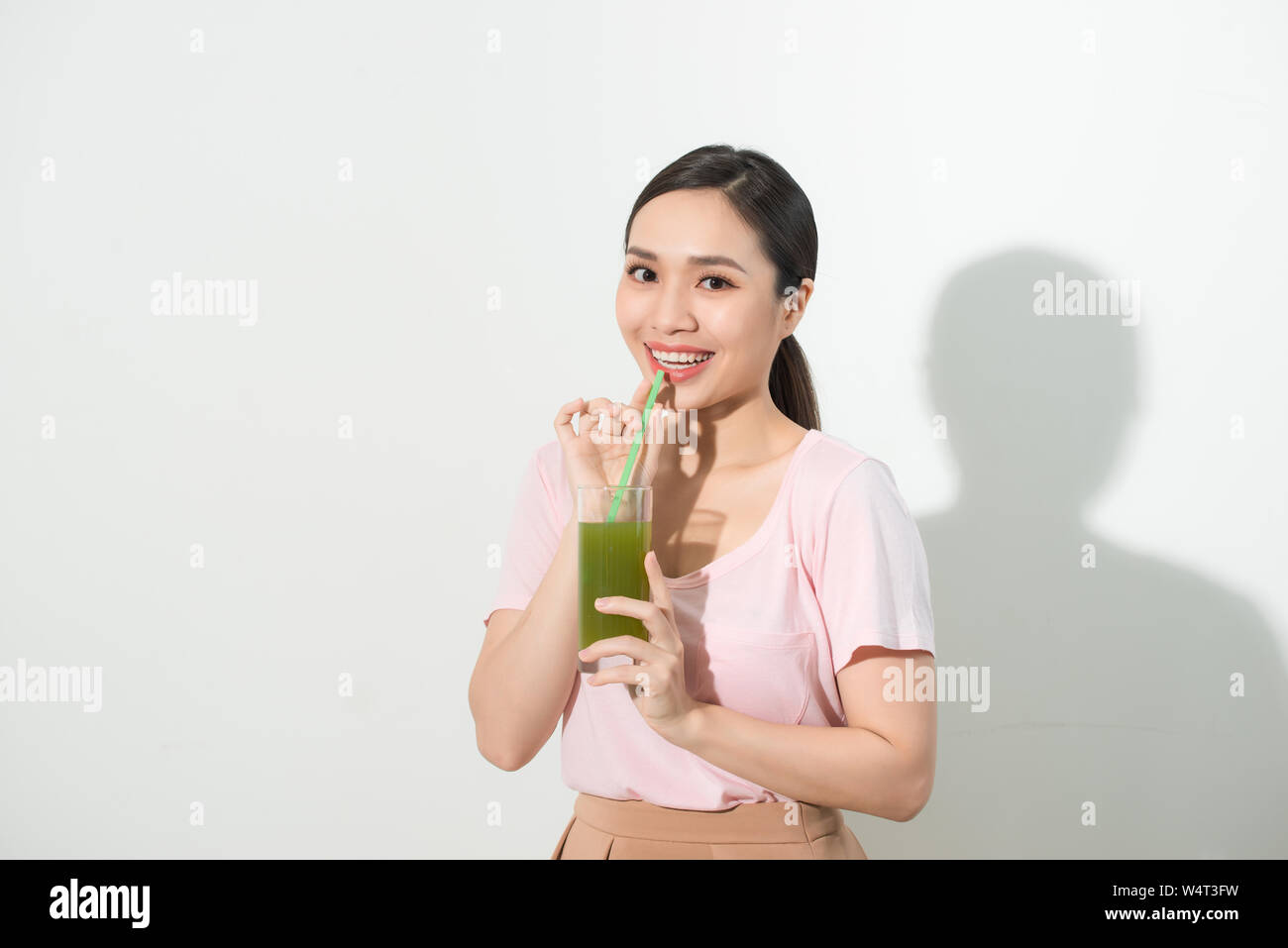 Go green. Young beautiful woman enjoying a healthy raw fruit vegetable juice. Studio shot. Stock Photo