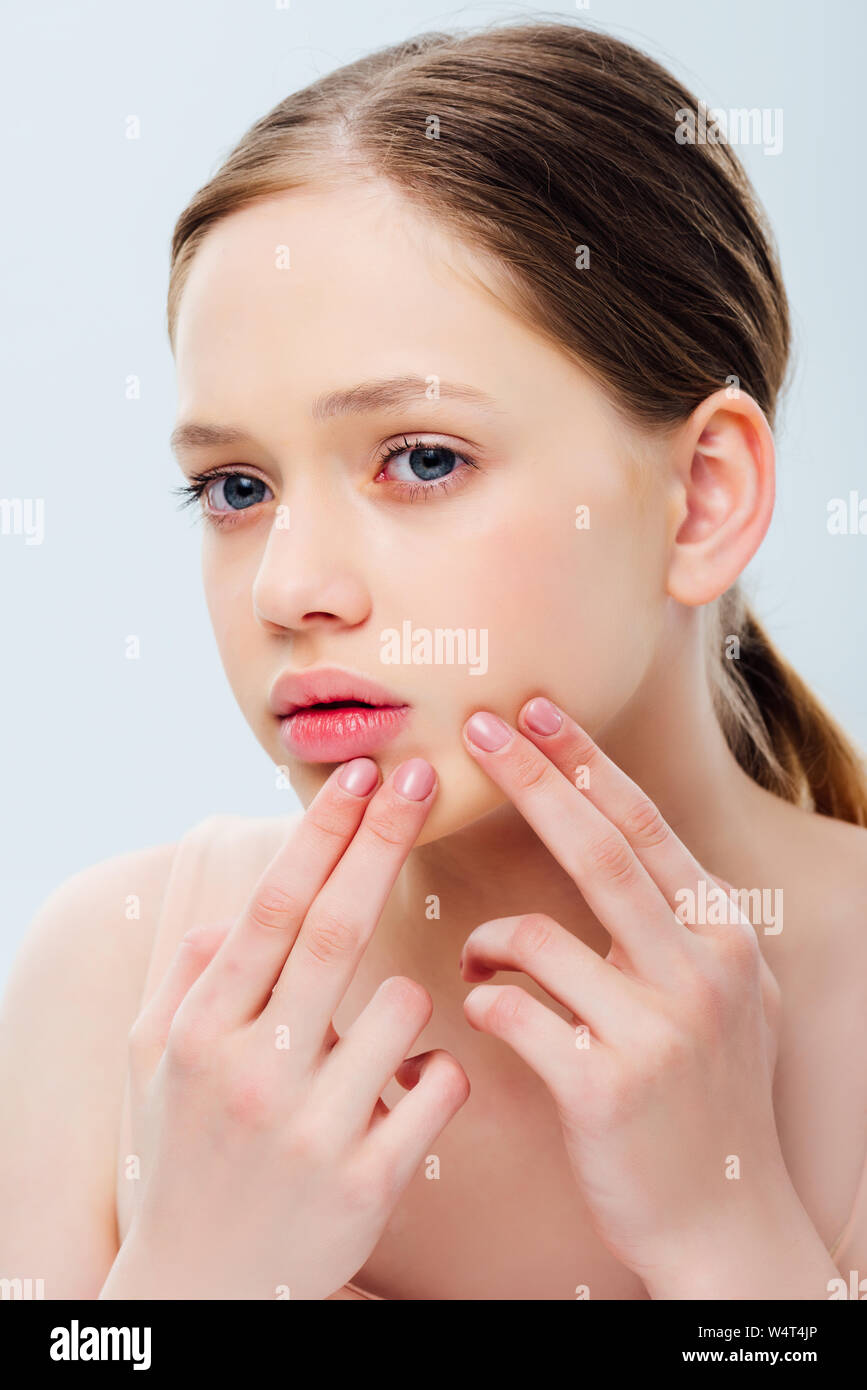 upset teenage girl with acne touching face isolated on grey Stock Photo
