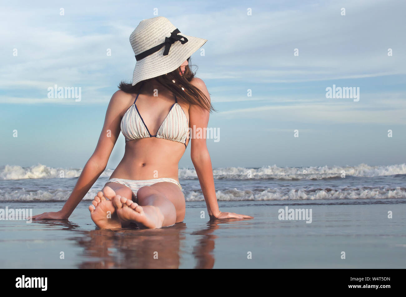 Teenager sitting on beach at water's edge wearing, Argentina Stock Photo
