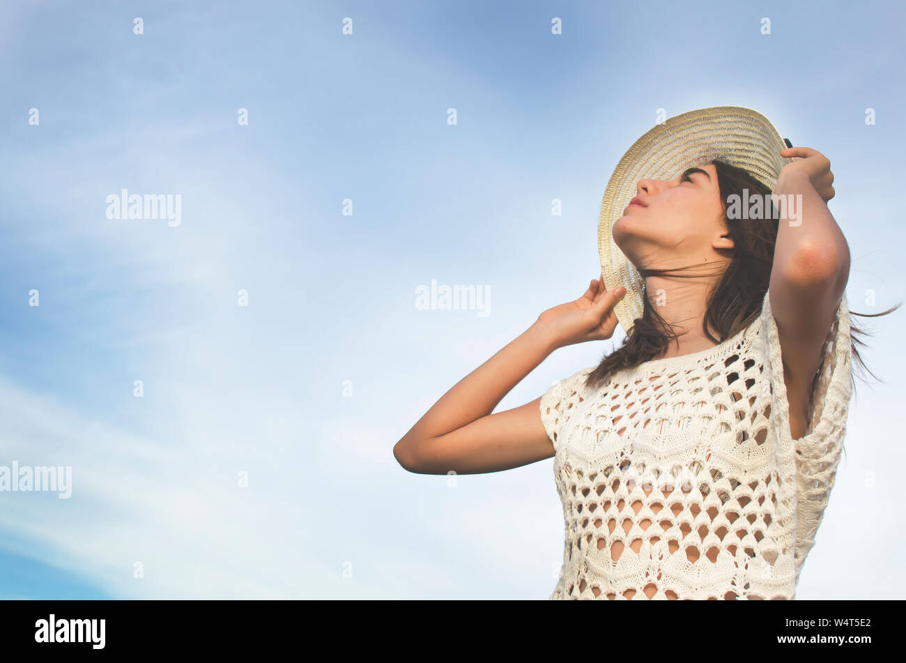 Teenager standing on beach holding her hat, Argentina Stock Photo