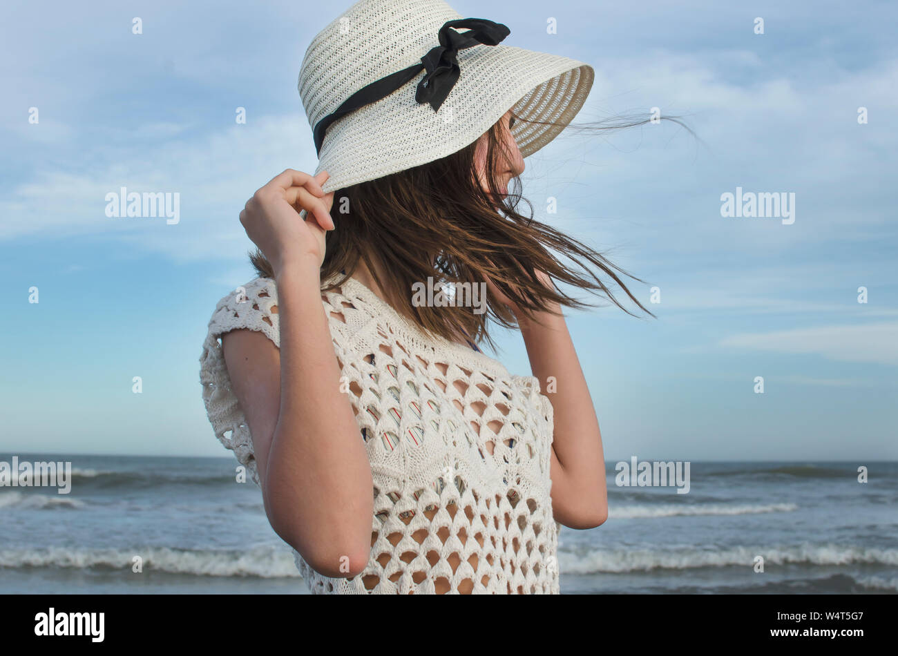 Teenage girl standing on beach holding her hat, Argentina Stock Photo