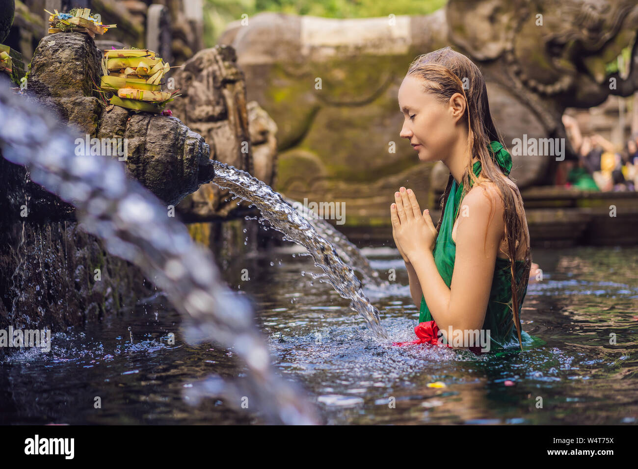 Woman in holy spring water temple in bali. The temple compound consists of a petirtaan or bathing structure, famous for its holy spring water Stock Photo