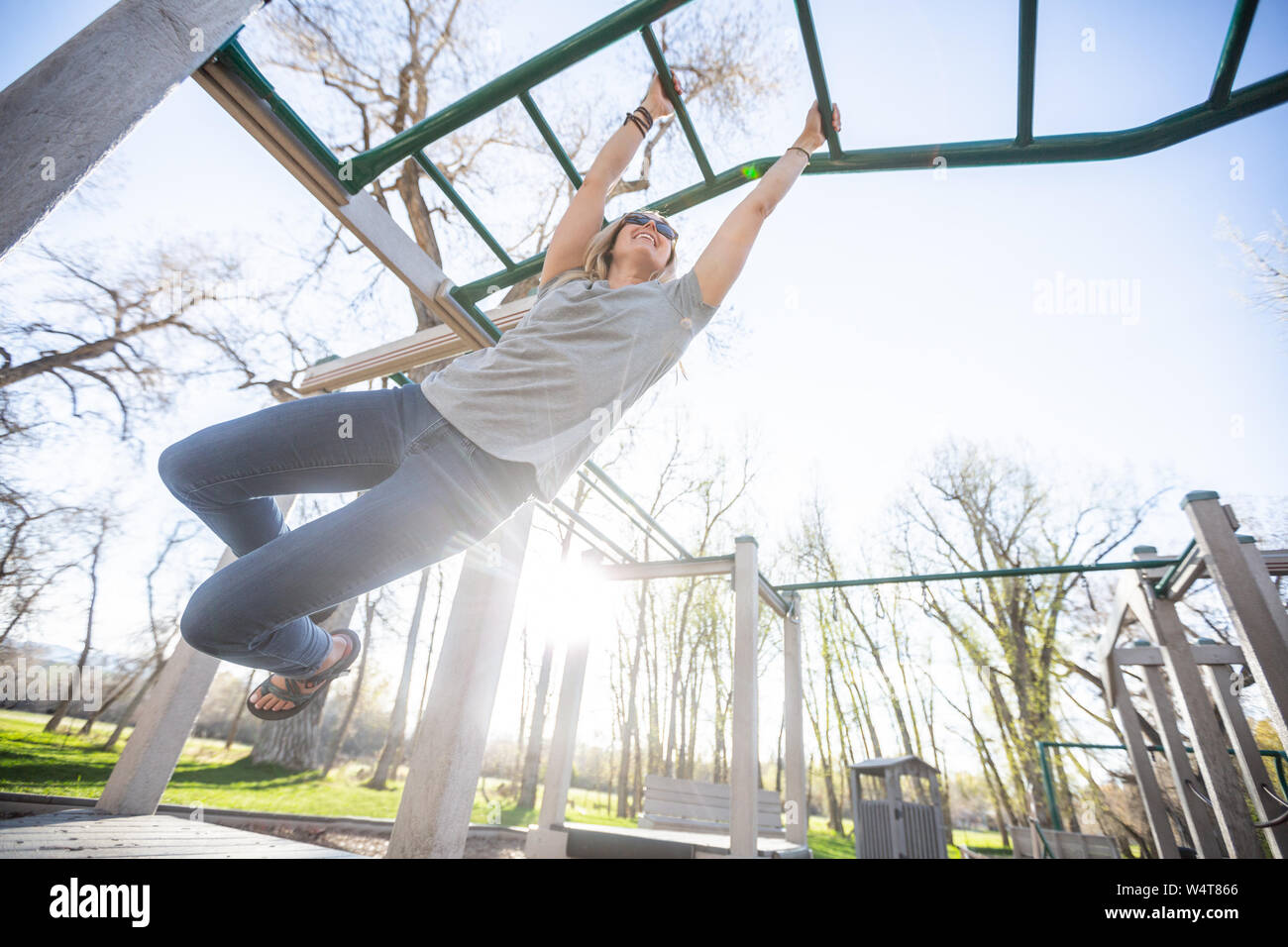 Woman playing on monkey bars in a playground, United States Stock Photo