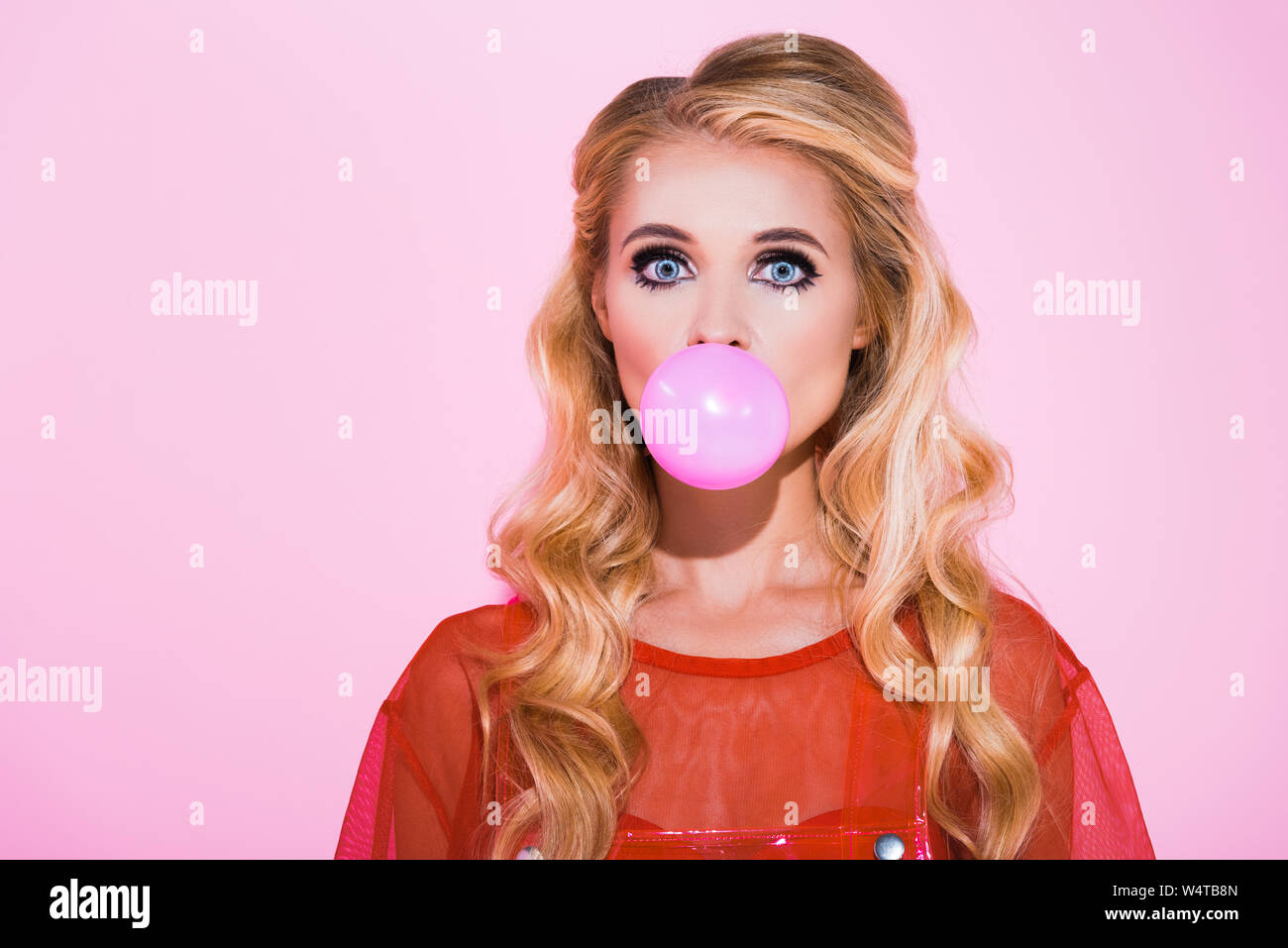 beautiful girl blowing bubble gum isolated on pink, doll concept Stock Photo