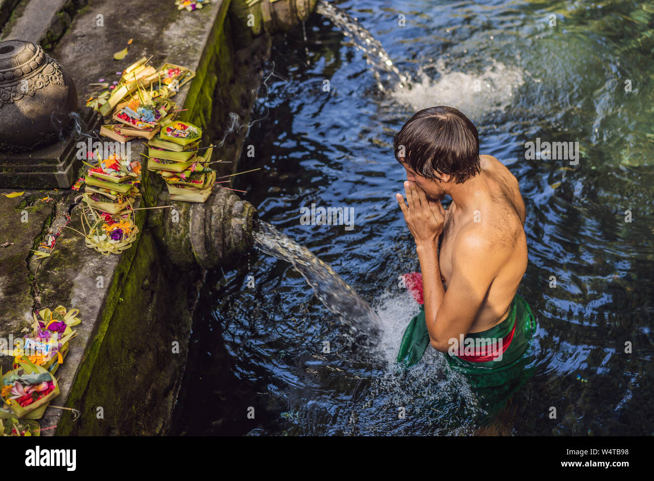 Man in holy spring water temple in bali. The temple compound consists of a petirtaan or bathing structure, famous for its holy spring water Stock Photo