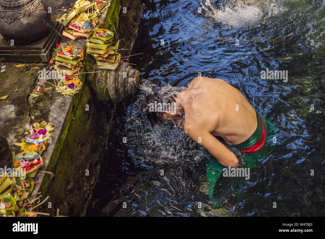 Man in holy spring water temple in bali. The temple compound consists of a petirtaan or bathing structure, famous for its holy spring water Stock Photo