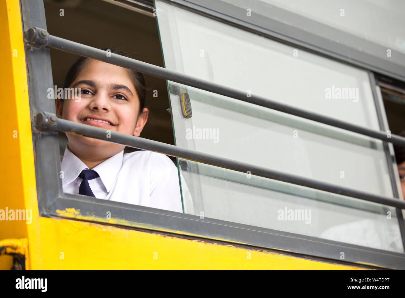 Happy school children looking from window of school bus Stock Photo