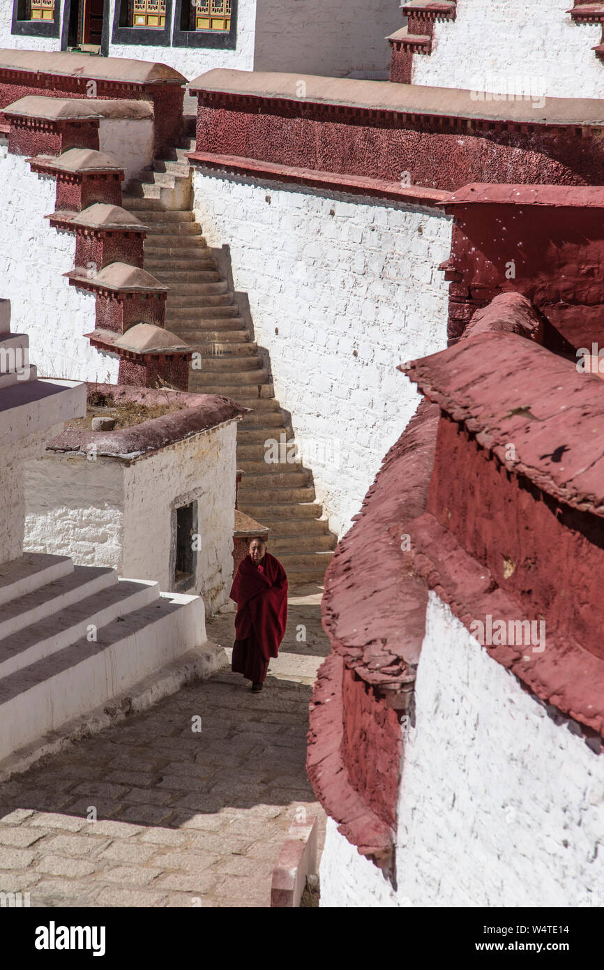 China, Tibet, Lhasa, A monk walks up a steep cobblestone walkway in the Ganden Buddhist Monastery which sits at the top of a natural amphitheater on Wangbur Mountain. It  founded in 1409 AD but was mostly destroyed in 1959 by the Chinese military. Stock Photo