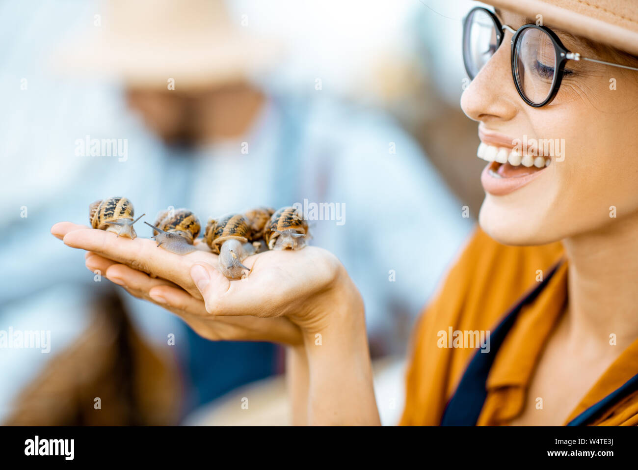 Close-up portrait of a young woman holding snails, taking care of them in the farm for snails growing Stock Photo