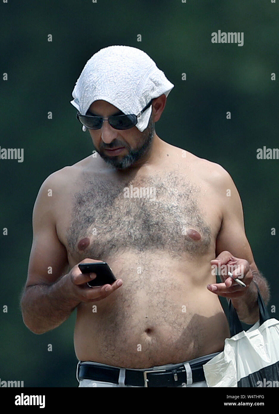 A man shades his head with a flannel in Hyde Park, London, after  temperatures climbed above 30C in some parts of the UK after a tropical  night, as the country braces for