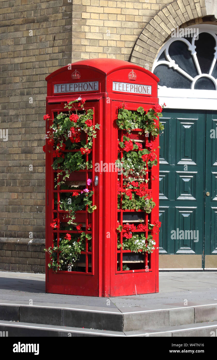 Recycled iconic British red telephone box now in use as a plant display holder in Bath city centre outside Bath Spa station on sunny day in July 2019. Stock Photo