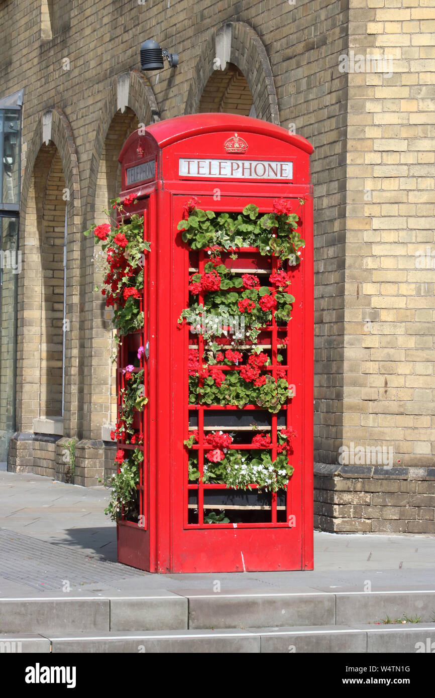 Recycled iconic British red telephone box now in use as a plant display holder in Bath city centre outside Bath Spa station on sunny day in July 2019. Stock Photo