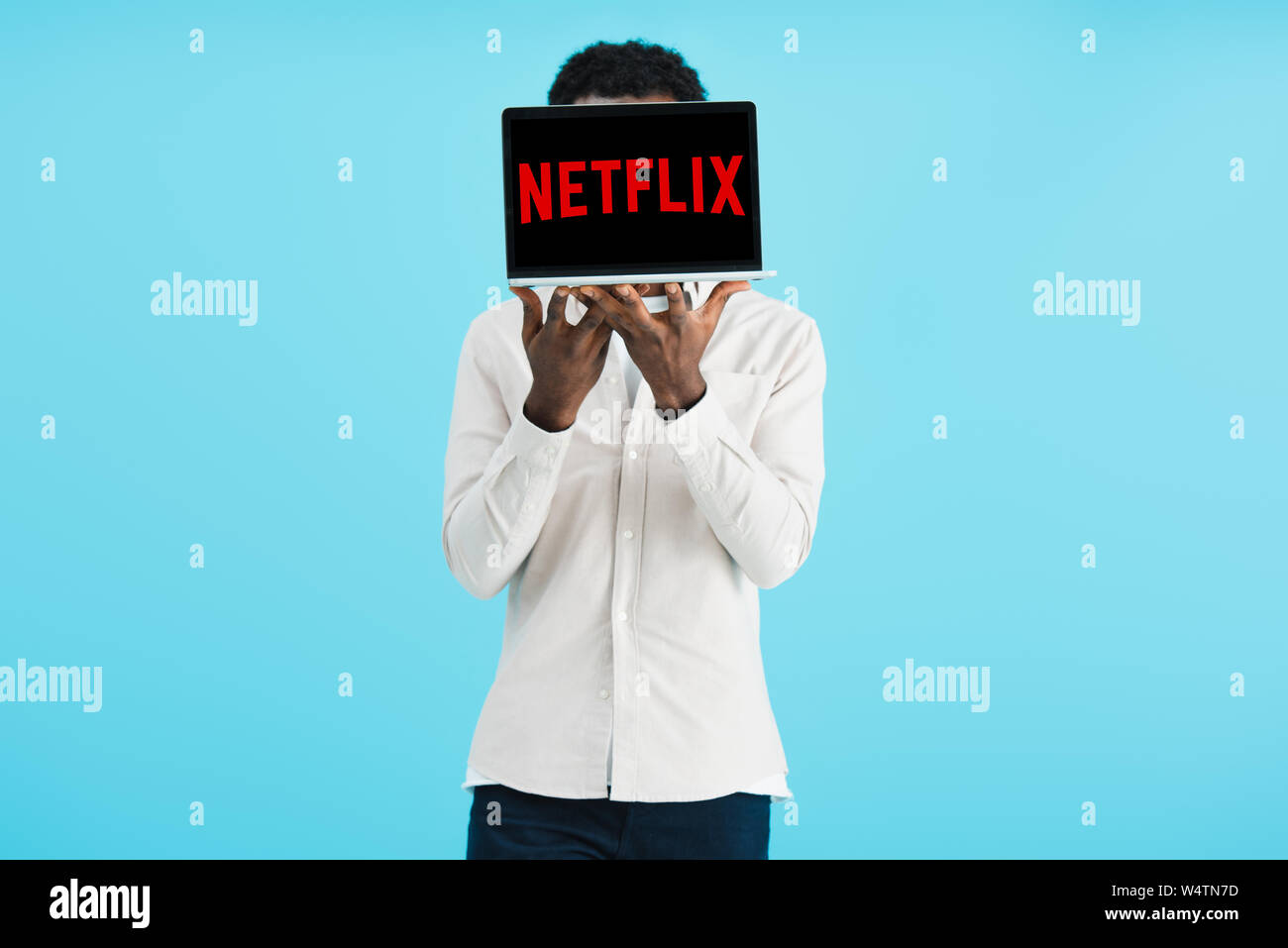 KYIV, UKRAINE - MAY 17, 2019: african american man showing laptop with netflix website, isolated on blue Stock Photo