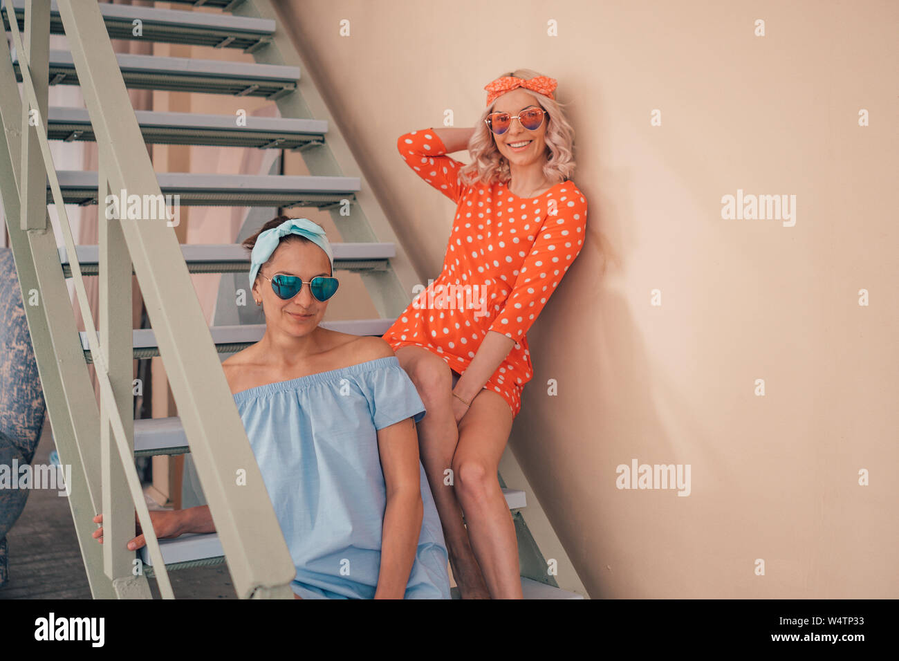 Sexy young girls in pin-up style pose on the stairs. Women's summer clothing  Stock Photo