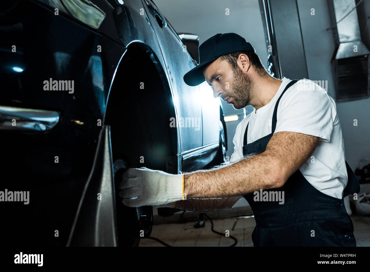 selective focus of car mechanic repairing automobile in car service