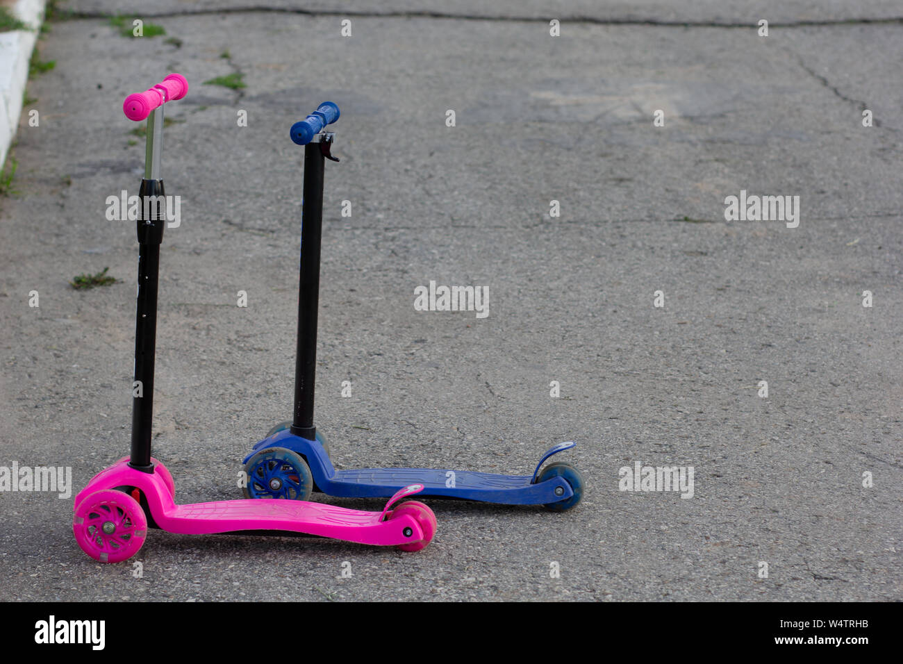 Two scooters without children, pink for girl, blue for boy on road Stock Photo