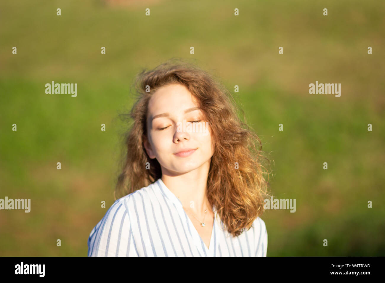 Portrait of beautiful young woman with closed eyes in the summer park ...