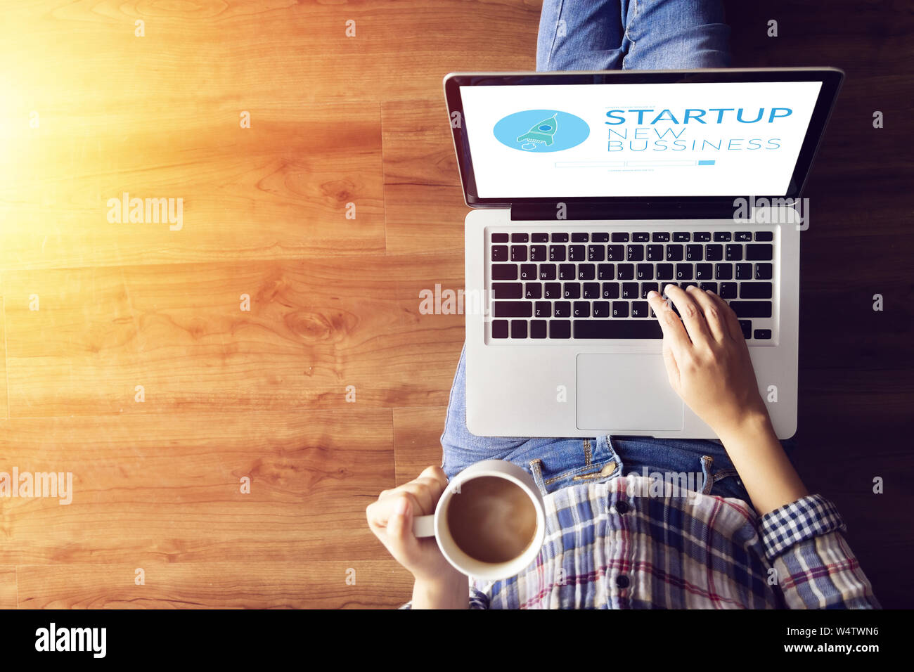 top view of people working on notebook laptop computer from home on wooden floor with startup business and rocket logo on screen, start up ideas busin Stock Photo