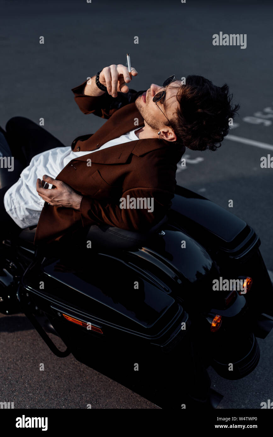 young man resting on motorcycle and smoking cigarette Stock Photo Alamy