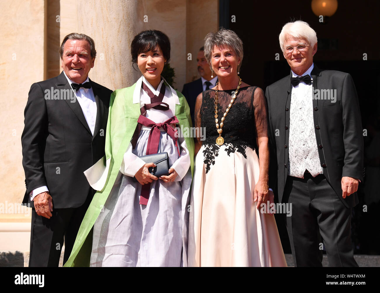Bayreuth, Germany. 25th July, 2019. The Lord Mayor of Bayreuth Brigitte Merk-Erbe (2nd from right) and her husband Thomas (r) welcome former Chancellor Gerhard Schröder (SPD) and his wife Soyeon Kim to the beginning of the Bayreuth Festival 2019. The Richard Wagner Festival begins in Bayreuth on Thursday. Numerous celebrities are expected on the red carpet. (To dpa 'Bayreuth Festival start in heat with new 'Tannhäuser'') Credit: Tobias Hase/dpa/Alamy Live News Stock Photo