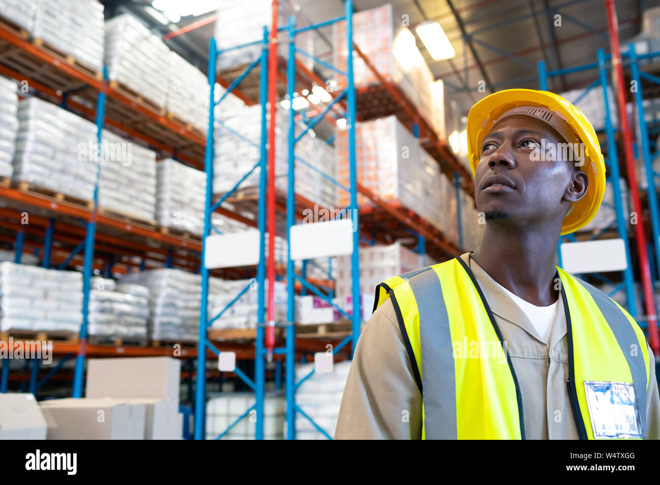 Thoughtful male worker looking away in warehouse Stock Photo