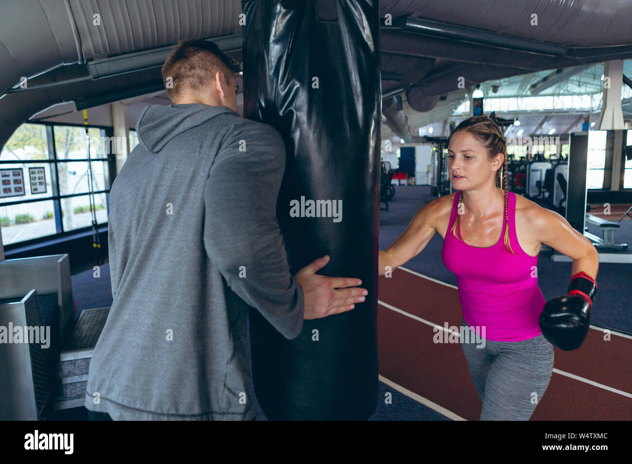 Male trainer giving boxing training to female athletic in fitness ...