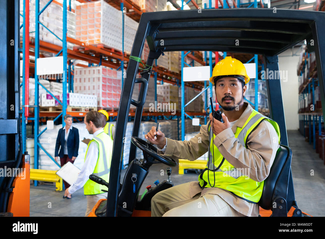 Male worker talking on walkietalkie while driving forklift in