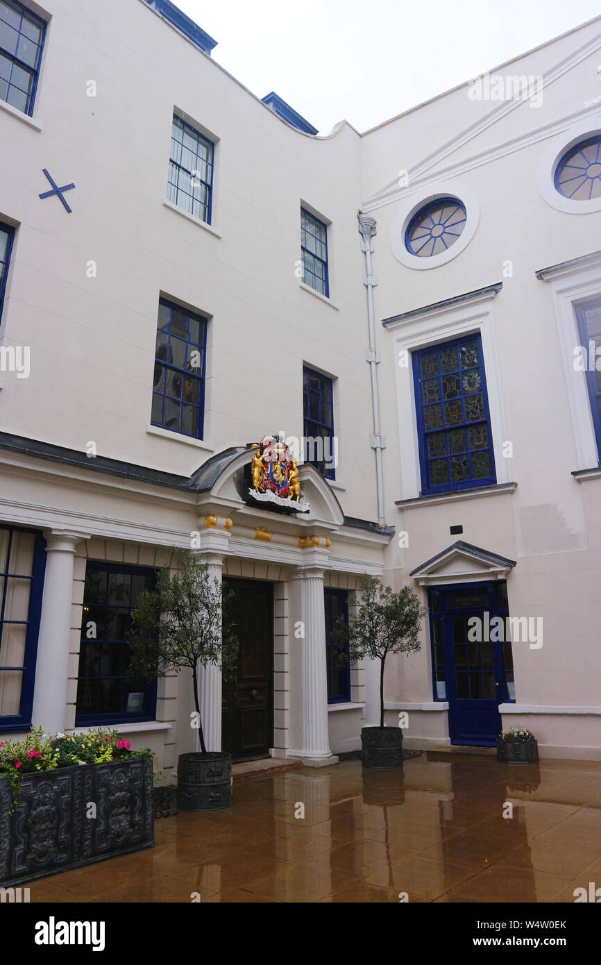 A photo of a house with blue framed windows and doors and various golden ornaments on the walls. The photo was taken in London, UK on a rainy morning. Stock Photo