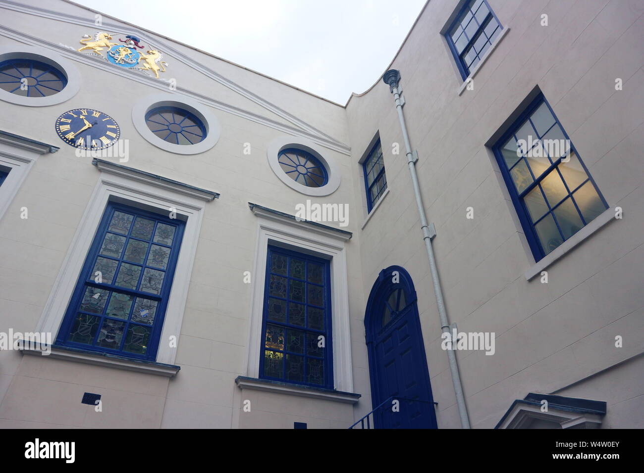 A photo of a house with blue framed windows and doors and various golden ornaments on the walls. The photo was taken in London, UK on a rainy morning. Stock Photo
