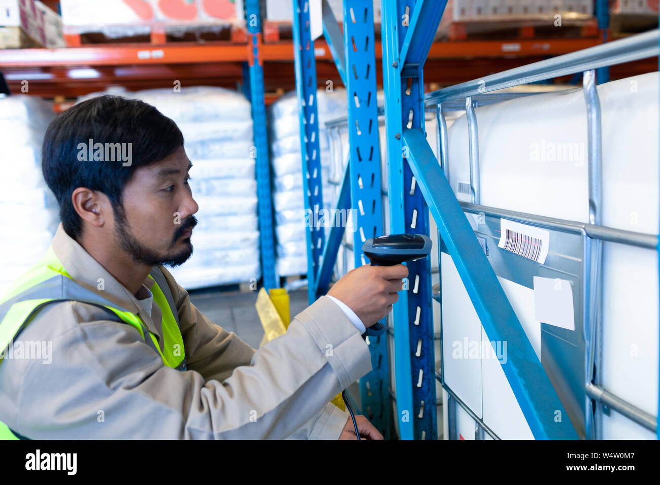 Male worker scanning package with barcode scanner in modern warehouse ...