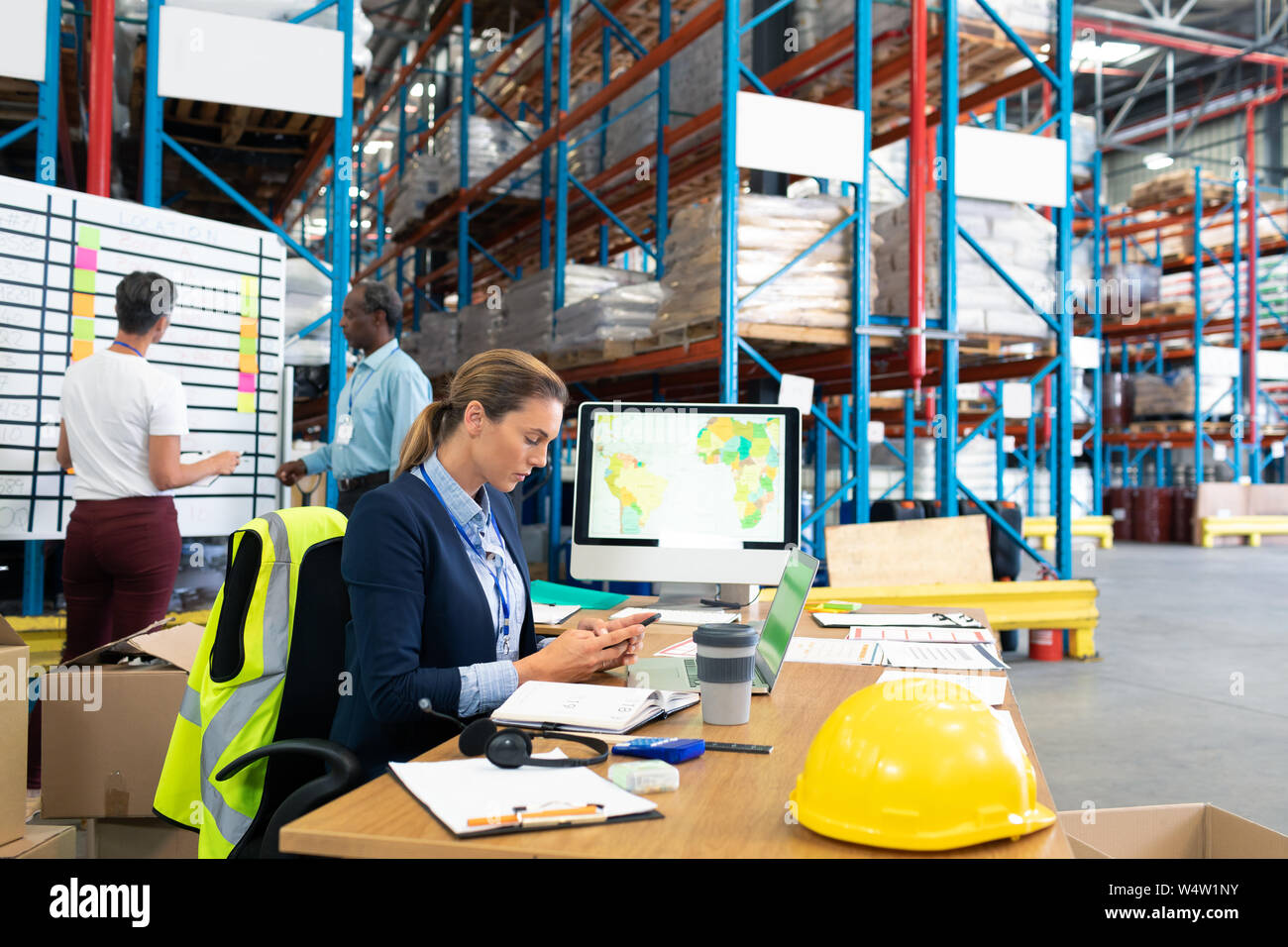 Female manager using mobile phone at desk Stock Photo