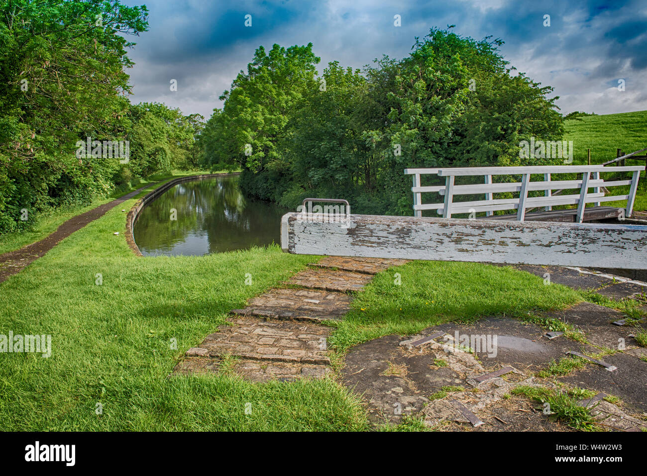 View of English rural countryside scenery on British waterway canal with lock during cloudy day Stock Photo