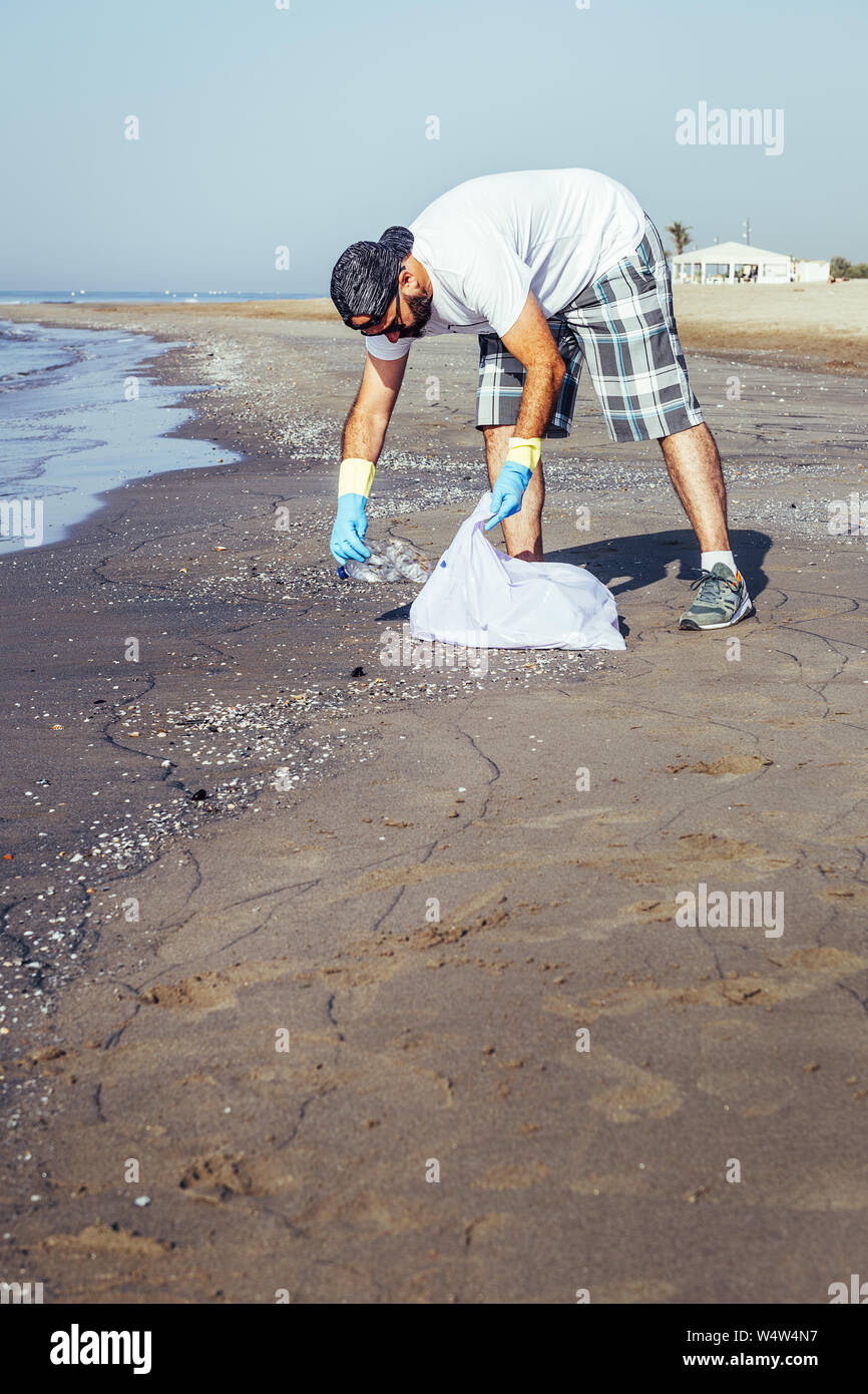 Kælder Banzai kursiv man collecting waste that pollute the ocean in plastic bag, people helping  to keep nature clean and picking up the plastics from sea, volunteer campai  Stock Photo - Alamy