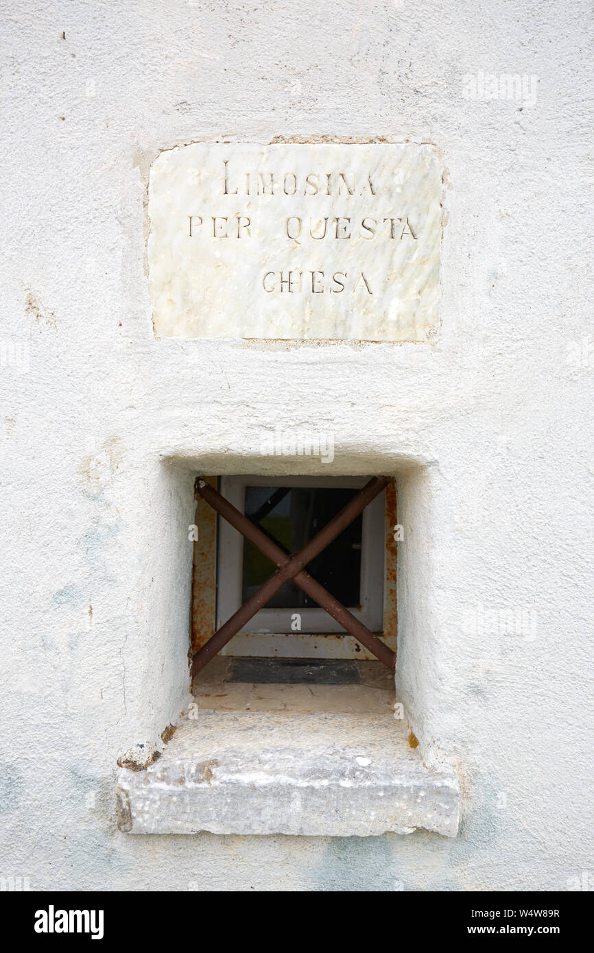 PRATO NEVOSO, ITALY - AUGUST 14, 2016: Virgin of the Snow ancient church on mountain top, small window for charity in Prato Nevoso, Italy. Stock Photo