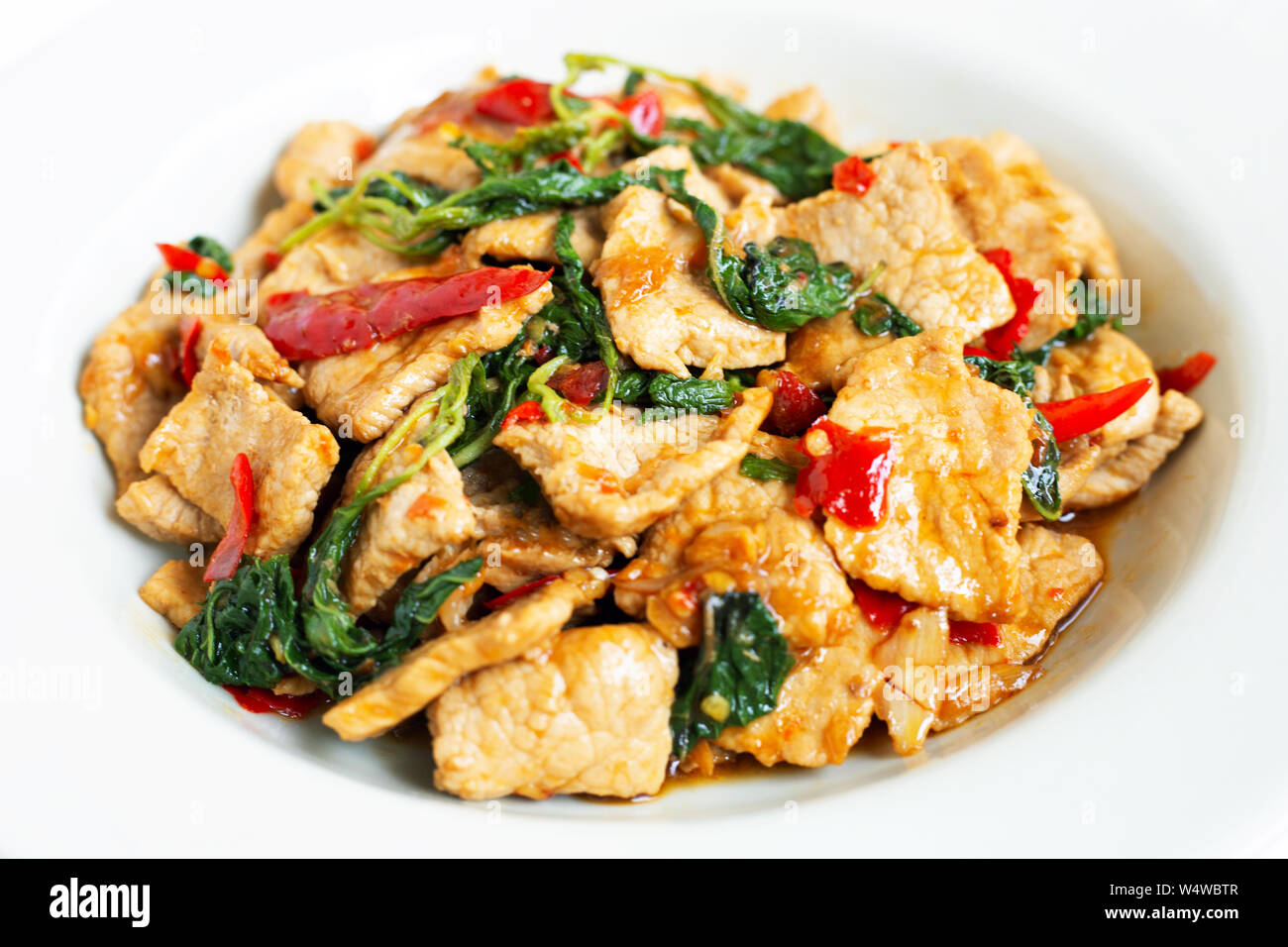 Stirfried hot and spicy pork with basil on white background Stock