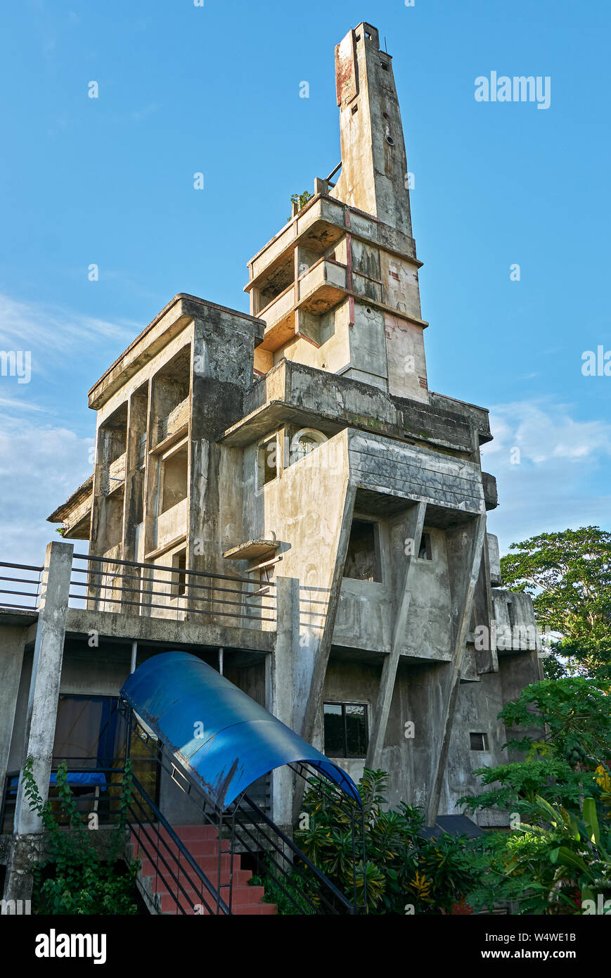 Low-angle view of an unusually unfinished weird concrete building with plenty floors, windows and a high tower. People living only in the ground level Stock Photo