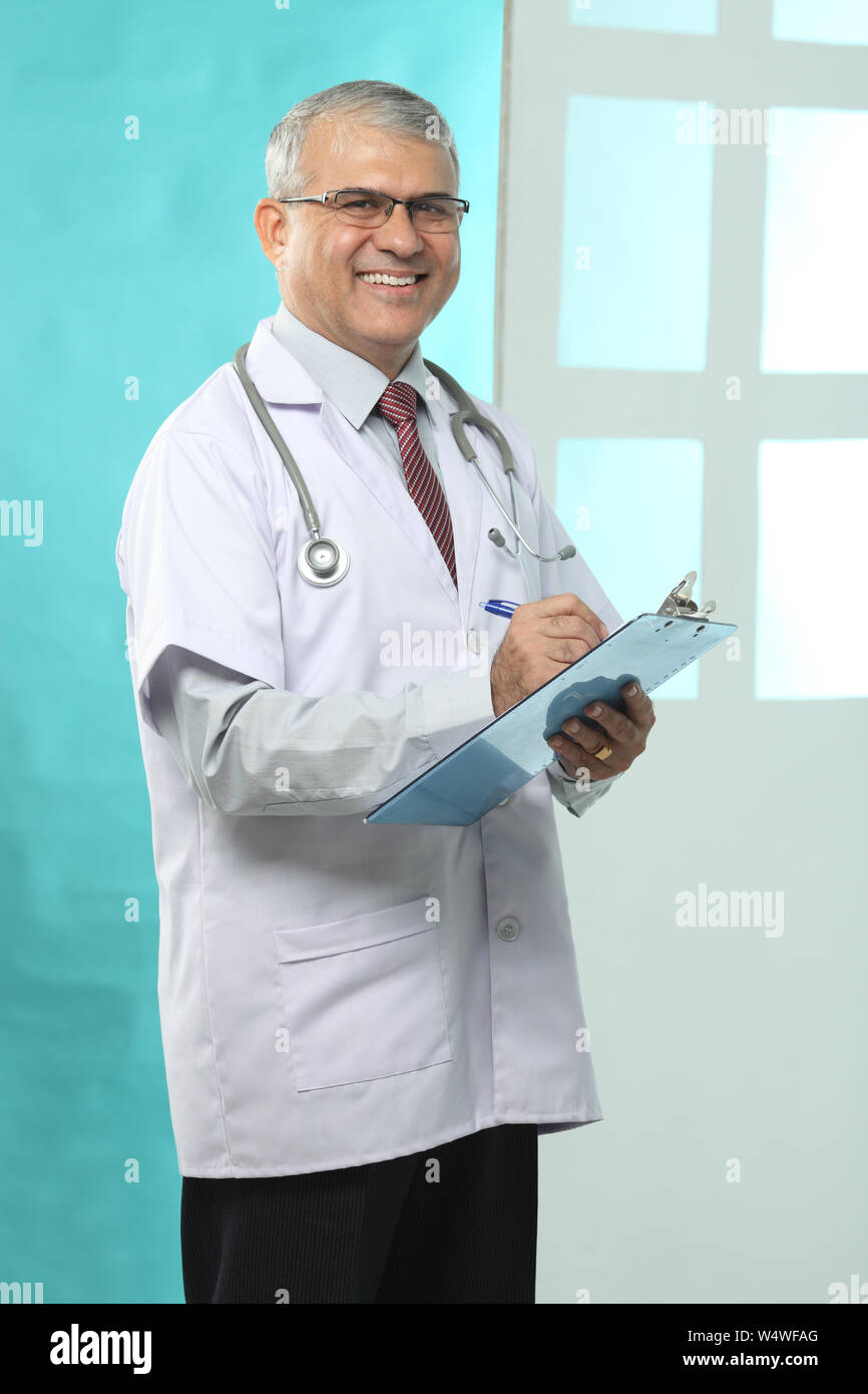 Male doctor writing prescription and smiling Stock Photo