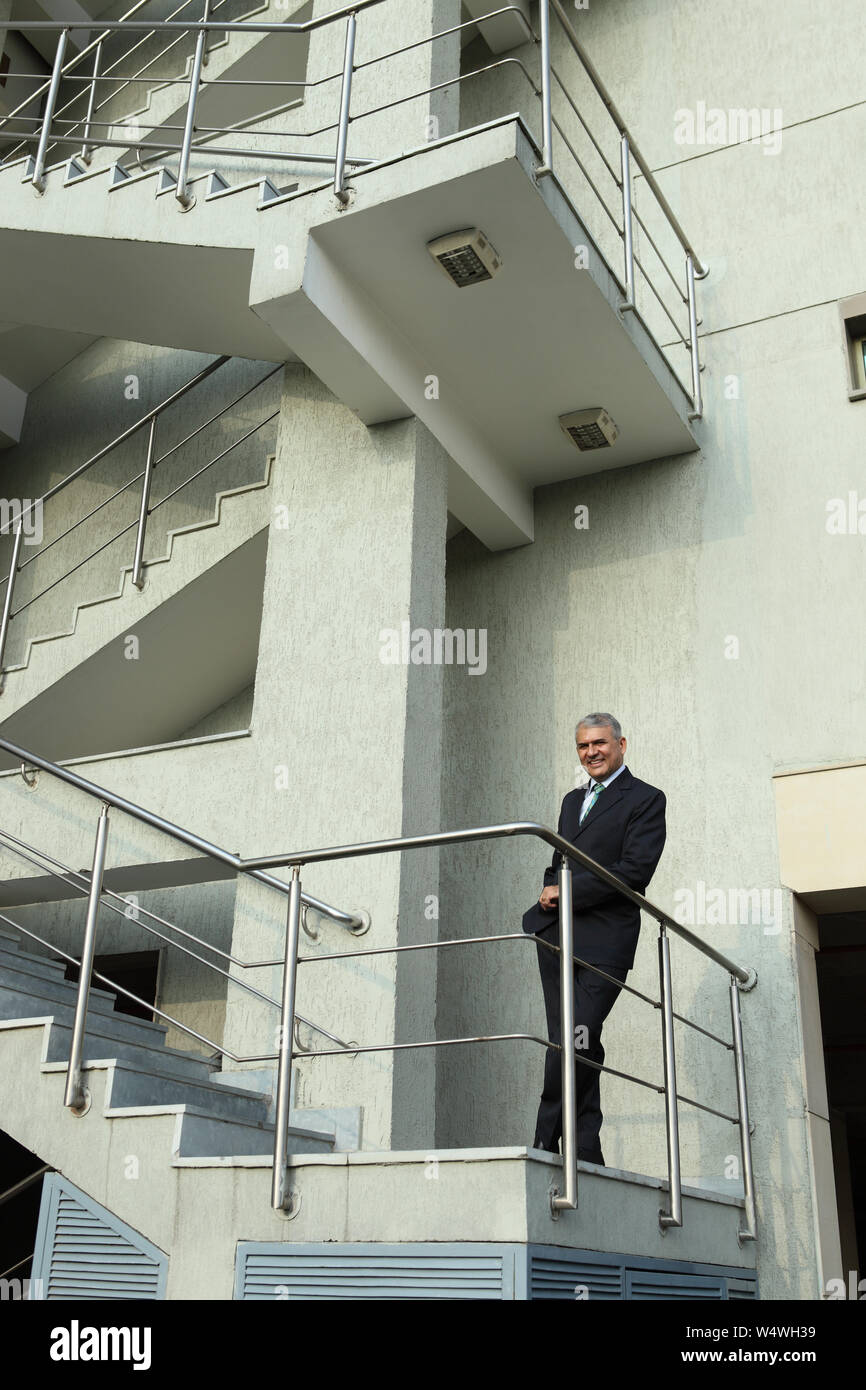 Lean Against The Railing Indian businessman leaning against railing Stock Photo - Alamy