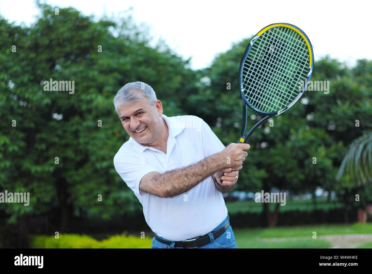 Man Using Tennis Racket Man playing a tennis racket and smiling Stock Photo - Alamy